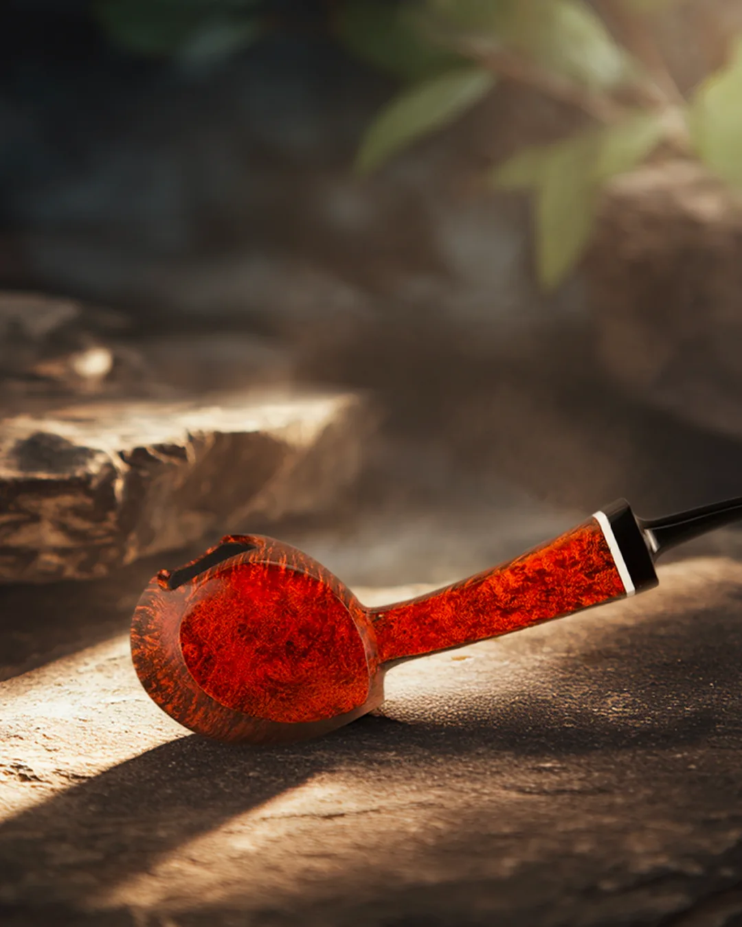 Pipa in legno rosso su una superficie materica, con luce calda e sfondo sfocato.